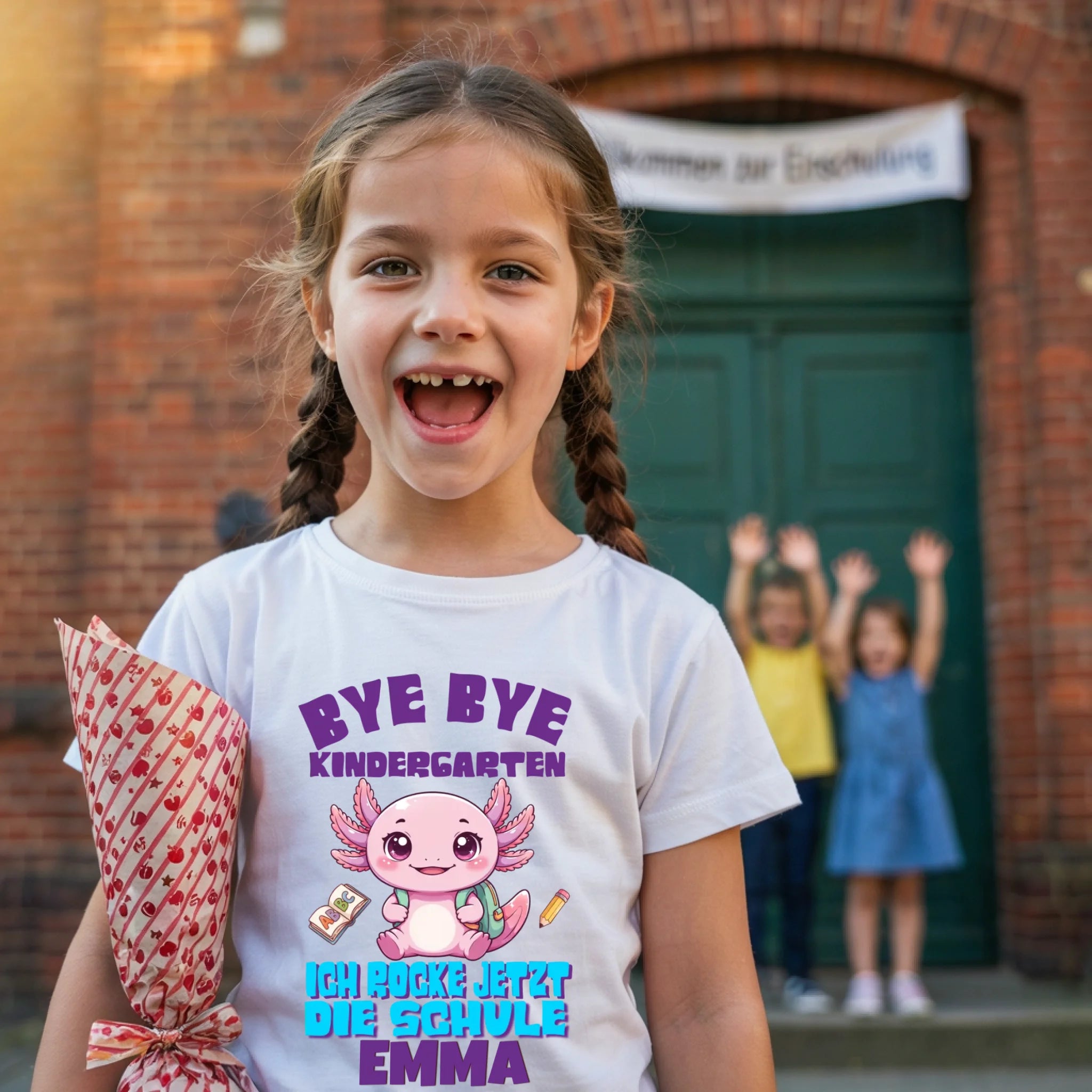Lachendes Mädchen mit Zahnlücke trägt Axolotl Einschulungs-Shirt mit Name Emma – Schulanfang 2026